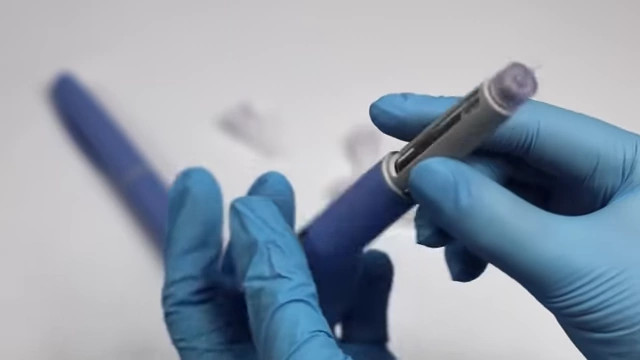 Gloved hands demonstrating the preparation of a semaglutide injection pen.