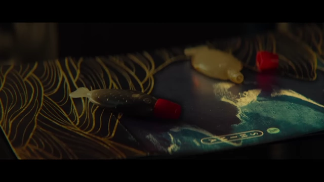 A close-up of a sushi box reveals two distinct lures, symbolizing the characters' contrasting traits but shared destiny.