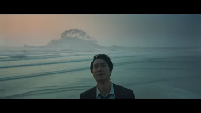 Hae-jun stands on the beach, looking out at the ocean with a distant rock formation resembling a mountain, symbolizing the unresolved connection between him and Seo-rae.