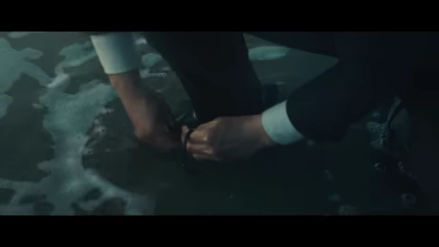 Hae-jun tying his shoelaces by the ocean, an example of recurring actions symbolizing his fixation.