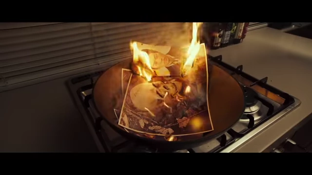 Photographs burning in a pan, symbolizing the destruction of memories and evidence, and the film's theme of obscuring truth.