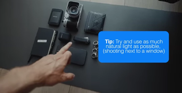 The arranged "everyday carry" items on a dark surface, with a tip to use natural light when shooting.