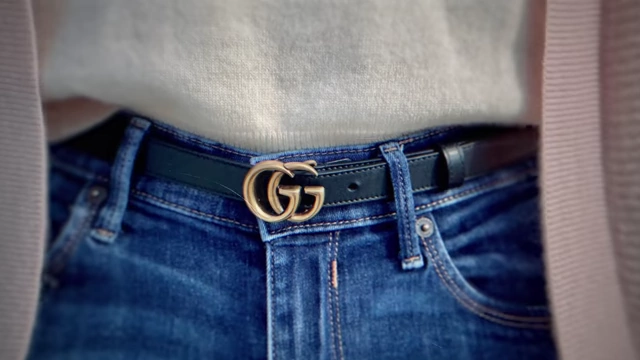 A close-up of a person wearing a Gucci belt with a prominent "GG" logo.
