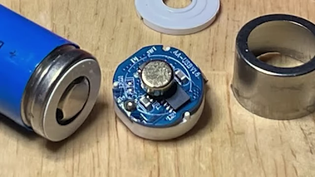 A disassembled lithium-ion AA battery, showing the voltage regulator circuit built into its cap