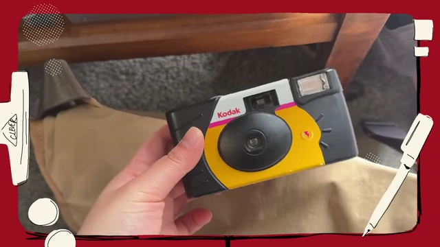 A hand holding a Kodak disposable film camera.