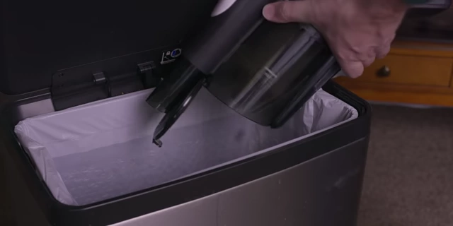 The cordless vacuum's dustbin with a compression slider that efficiently compacts debris for a mess-free ejection into a trash bin.