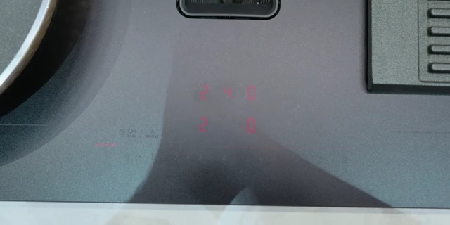 Close-up of the induction cooktop display indicating active cooking zones and temperature settings.