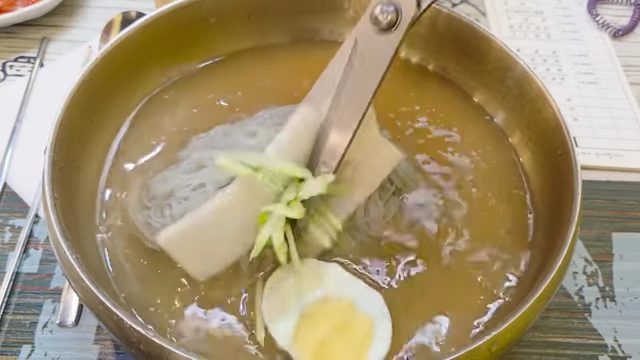 Cutting Naengmyeon noodles with scissors for easier eating