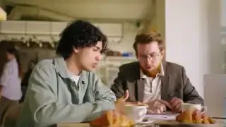 Zwei Männer sitzen in einem Café und unterhalten sich, einer davon könnte ein Accountability-Partner sein.