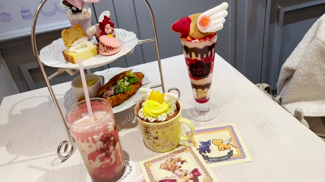 A two-tier afternoon tea set with various pastries and small savory items, along with two cups of tea.