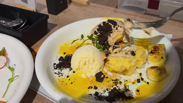 A dessert plate with slices of chiffon cake, vanilla ice cream, caramelized bananas, and cookie crumbles, themed after a character's necktie.