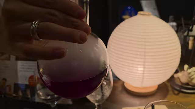 A beaker containing a purple liquid, with smoke emanating from it, next to a glass.