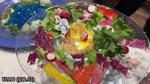 A salad pasta dish with colorful vegetables and character cutouts, featuring a light glowing from underneath.