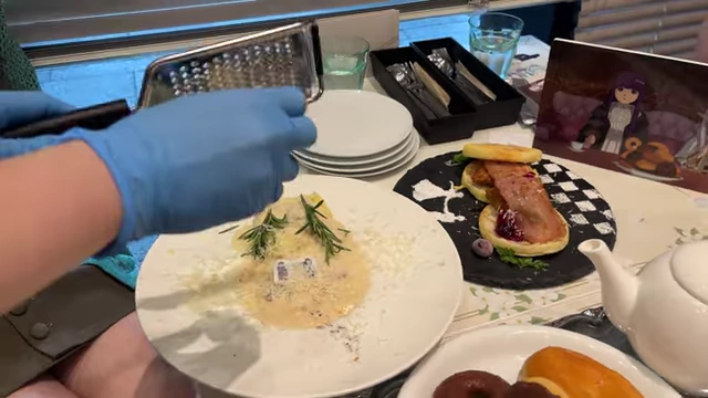 A staff member grating cheese over a cream doria dish to simulate snow.