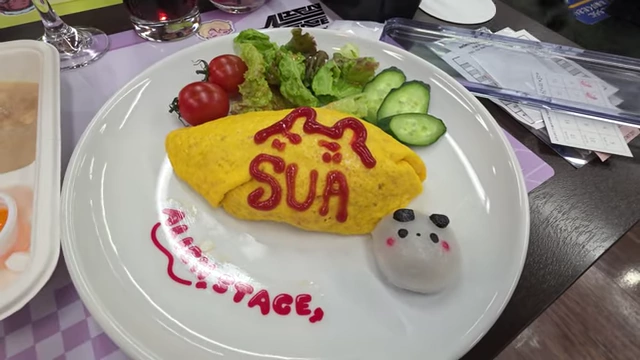An omurice dish with "Alien Stage" drawn in ketchup, served with a side salad and a pando mochi.
