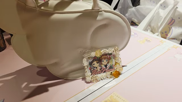 A small white photo frame with character art of Sakura and Tomoyo, adorned with pearls and flowers.