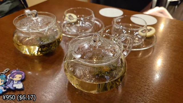 Two glass teapots with blooming teas, and empty teacups with character sugar cookies on the saucers.