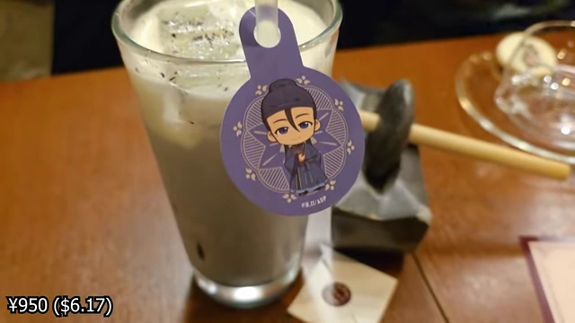 A black sesame latte with a character tag and a sachet of cinnamon.