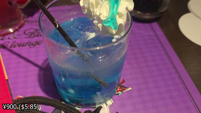 A blue lychee cider drink with whipped cream, pop rock candy, and a character decoration.