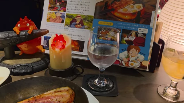 Table decorations featuring Calcifer candles and a mini Howl's Moving Castle art book.