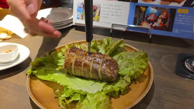 A roasted pork loin with a knife stuck in it, served on a bed of lettuce.