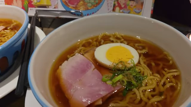 A bowl of ramen with ham and a boiled egg, served in a decorated bowl resembling the one from Ponyo.
