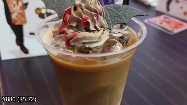 An iced coffee with chocolate whipped cream, raspberry drizzle, and bat-wing shaped wafers.