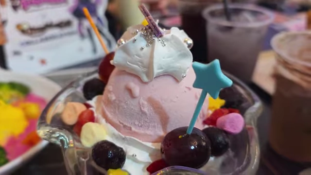 A dessert cup with layers of coffee jelly, strawberry ice cream, whipped cream, fruit, and marshmallows.