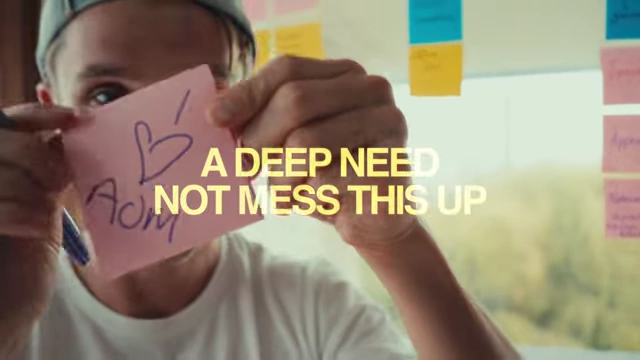 Evan holding a sticky note with "A DEEP NEED NOT MESS THIS UP" written on it, reflecting the pressure and determination to succeed with Art of Mondays.