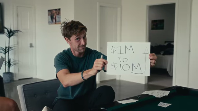 Evan holding a paper illustrating the "$1M to $10M" growth target, symbolizing their ambitious scaling plan.