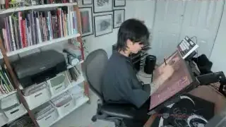 The artist working on her digital art, viewed from above her desk.