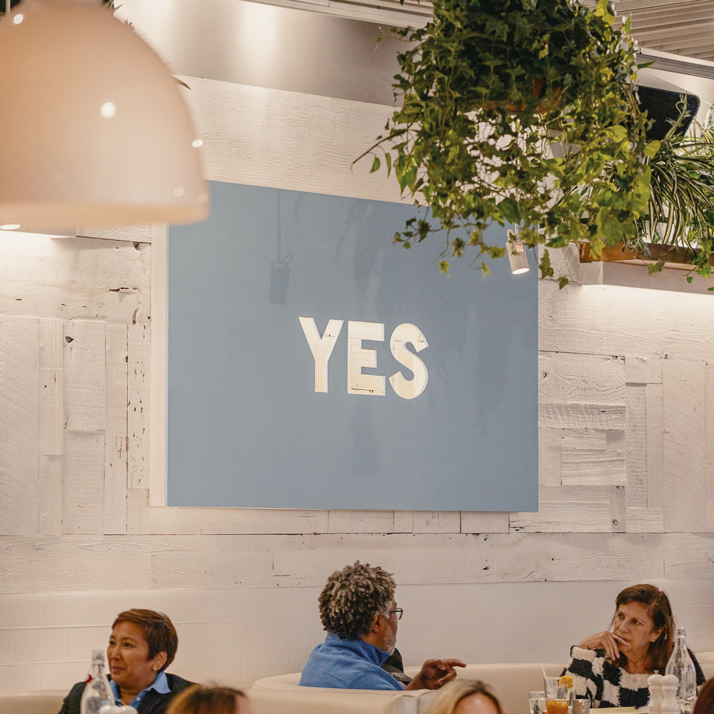 Yes Sign in dining room with people at tables