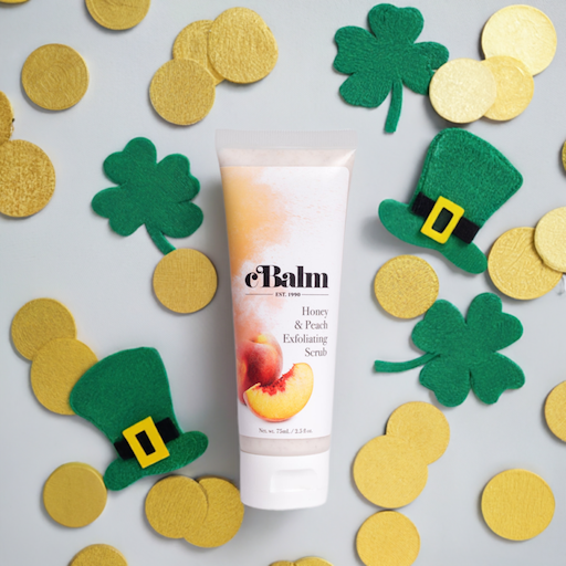 a tube of a skincare product surrounded by cutouts of green leprechaun hats, clovers, and gold coins