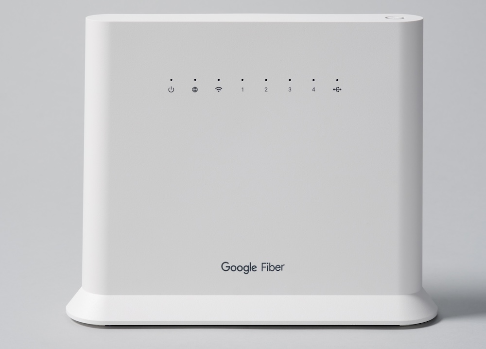 Front view of the Google Fiber Wi-Fi 6 Router (GRAX210T). On the top right is a power button. Along the front of the router are LEDs (L-R): Power, WAN/Internet, Wi-Fi, LAN 1-4, USB. The Google Fiber logo is printed near the bottom.
