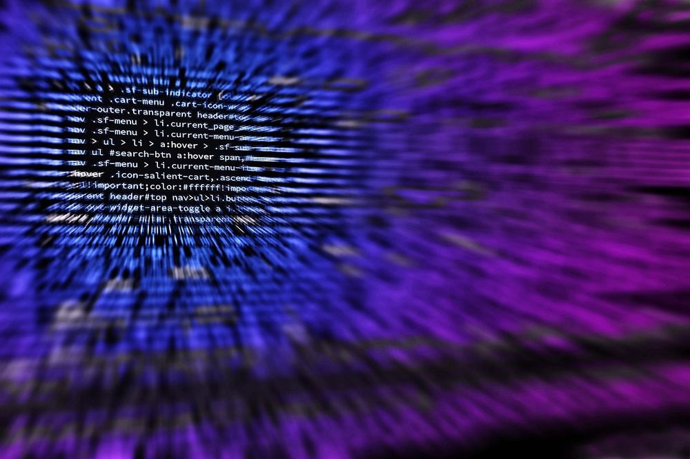 Blurred close-up of website code on a screen, lit in blue and purple.