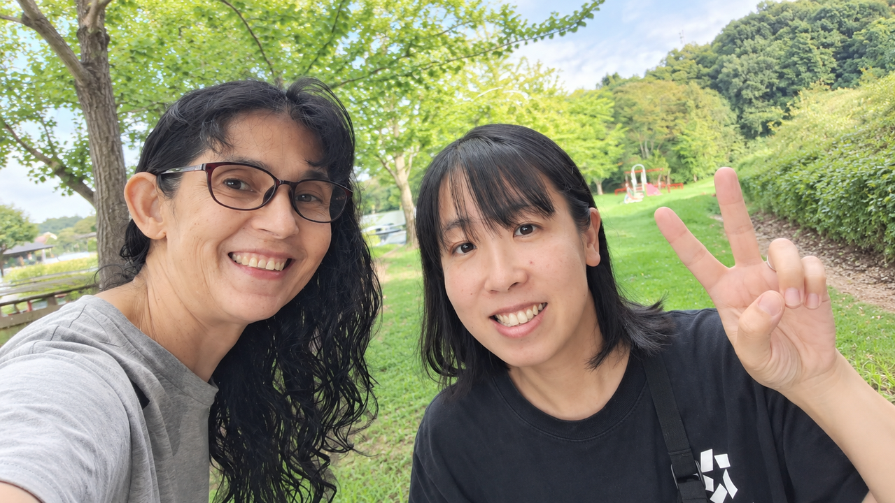 緑がまぶしい公園を背景に、フラビアさんと曽田が並んで笑顔でうつっている。