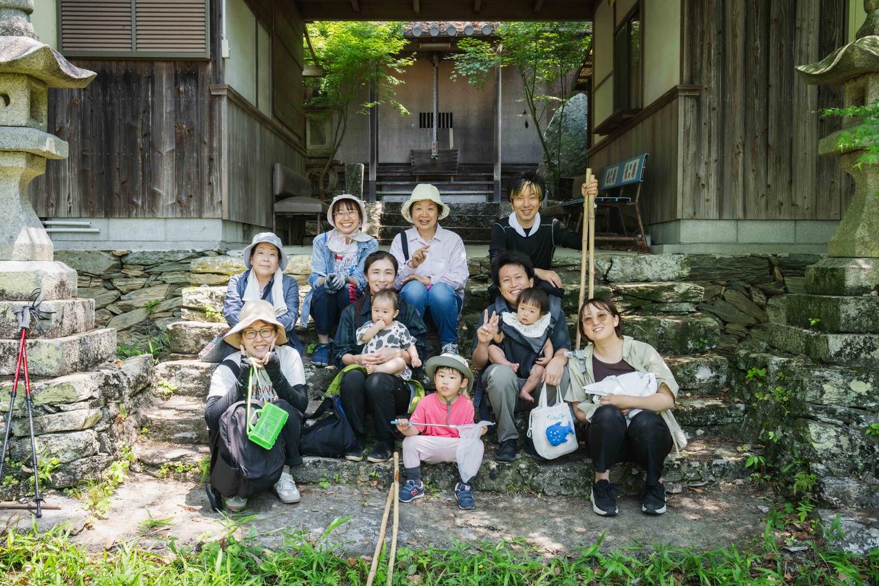 お堂の掃除を終えた人たち10数名が笑顔でお堂の前で座っている
