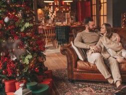 Mladi bračni par uživa na kauču u svom stanu koji je ukrašen za Božić