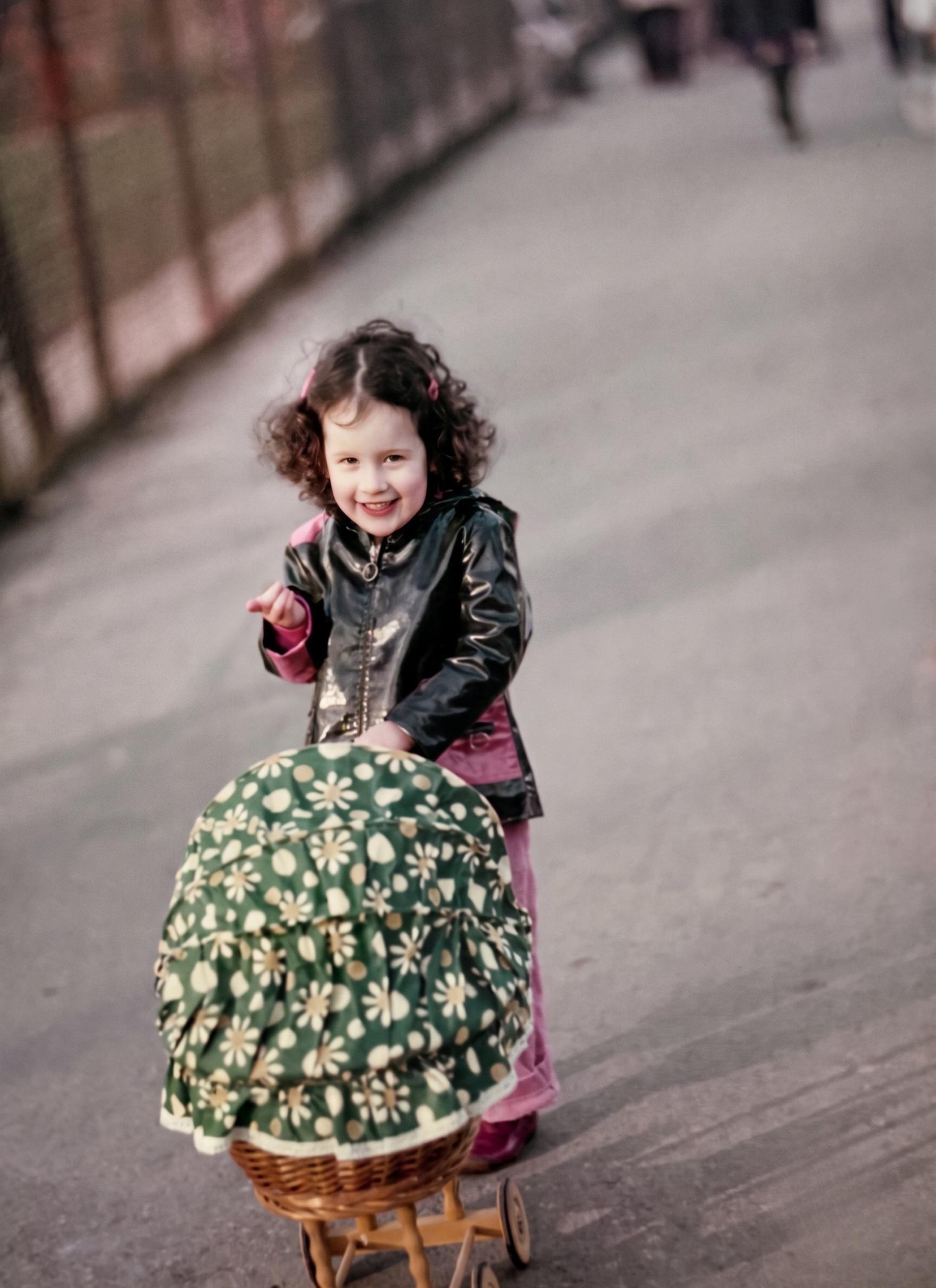 Tashi as a young child, smiling while pushing a toy pram