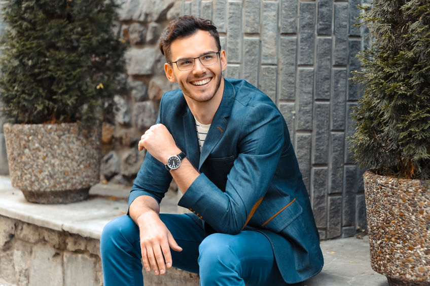 An image of man with glasses cheerfully smiling to illustrate ways to increase your attractiveness.