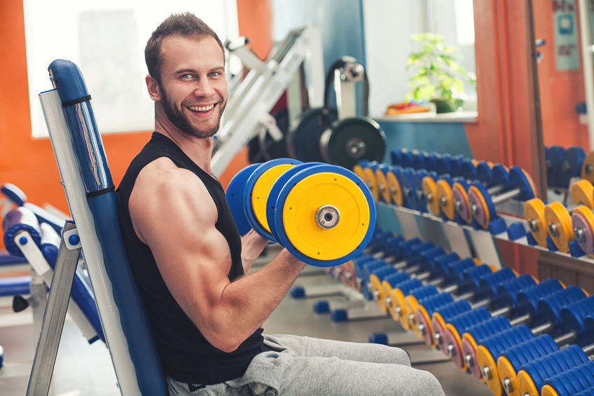 An image of young smiling athelete lifting weight in the gym
