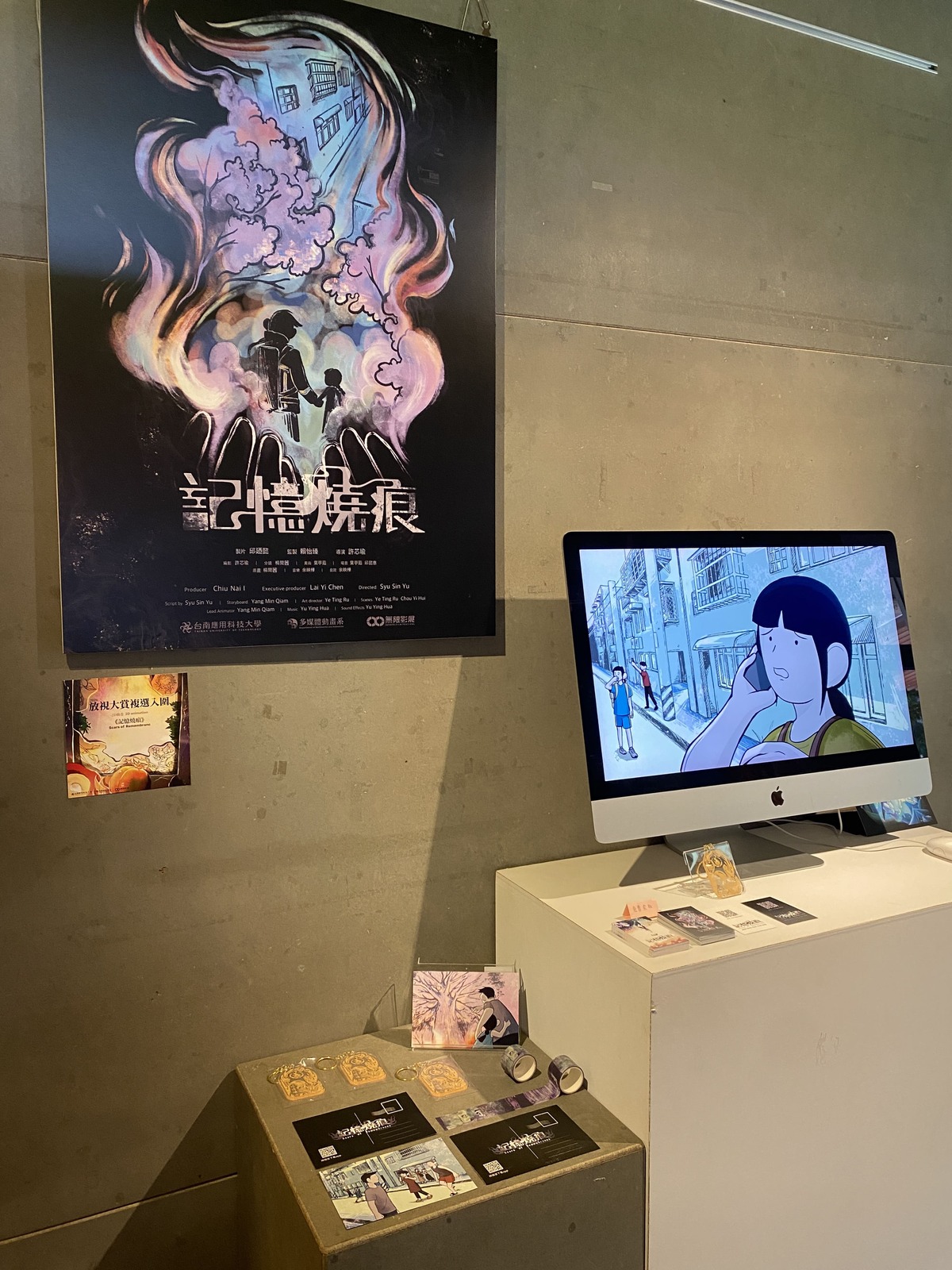 牆面貼海報，電腦展示動畫，桌面上擺放周邊