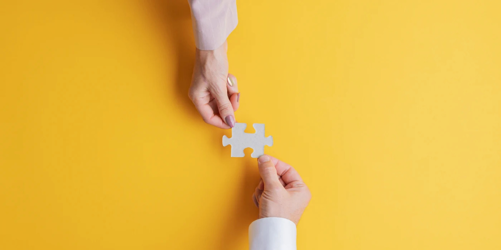 Two hands holding a puzzle piece 