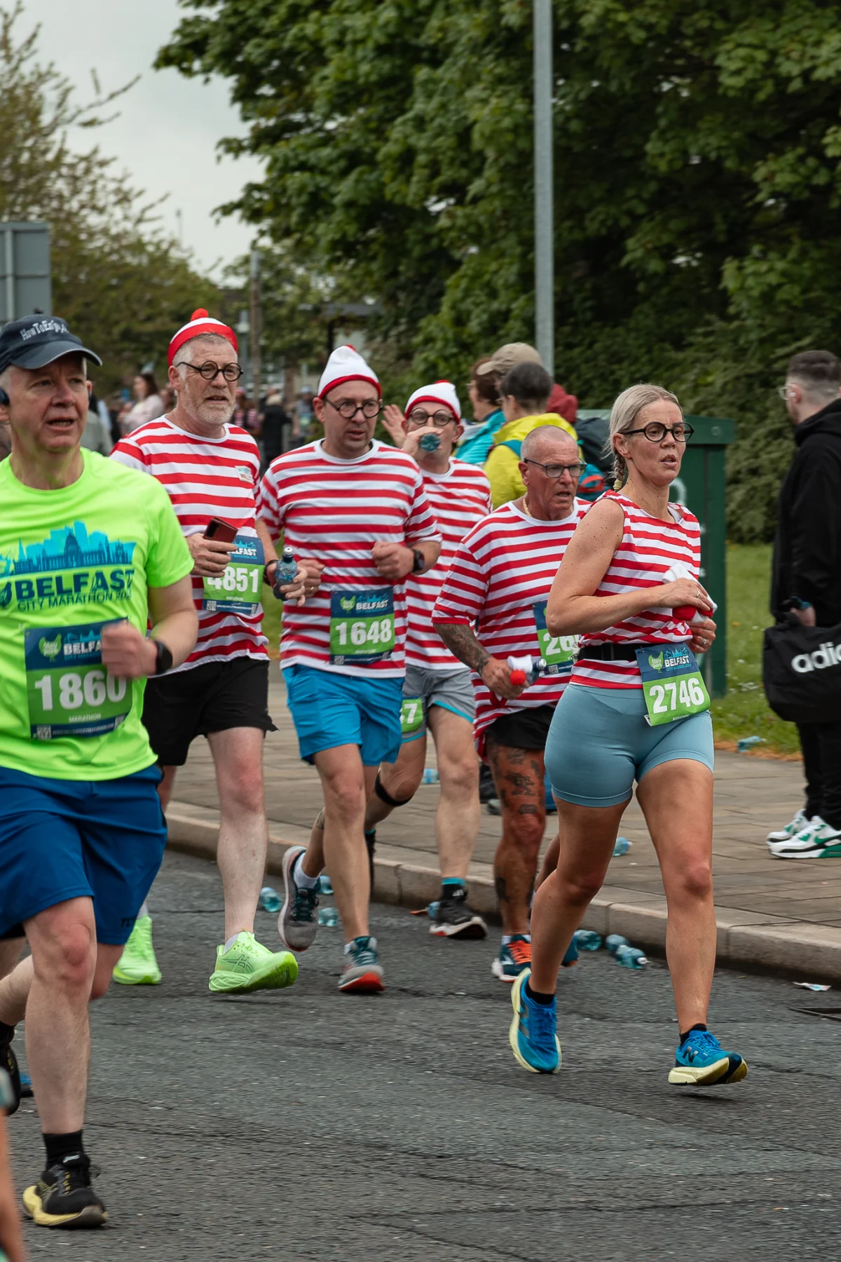 Group of runners in red and white striped shirts participating in the Belfast City Marathon.