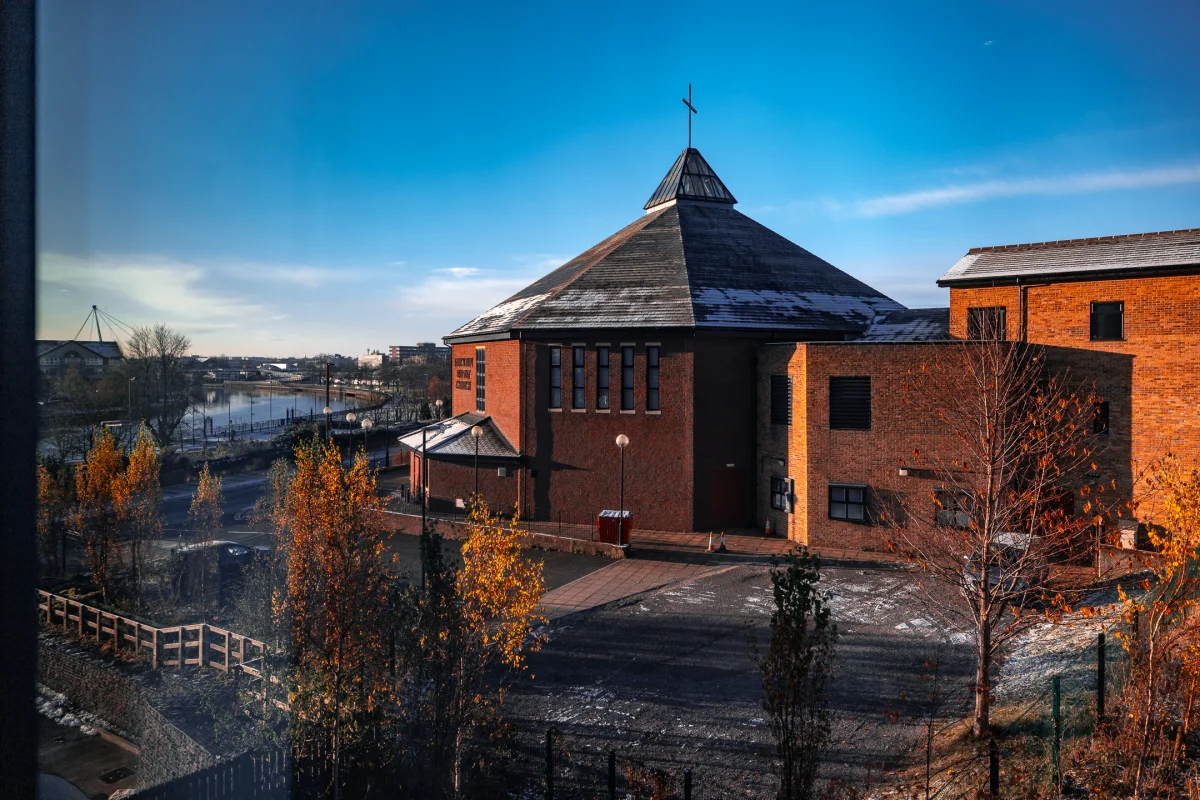 A modern brick church with a pointed roof under a clear blue sky during autumn.