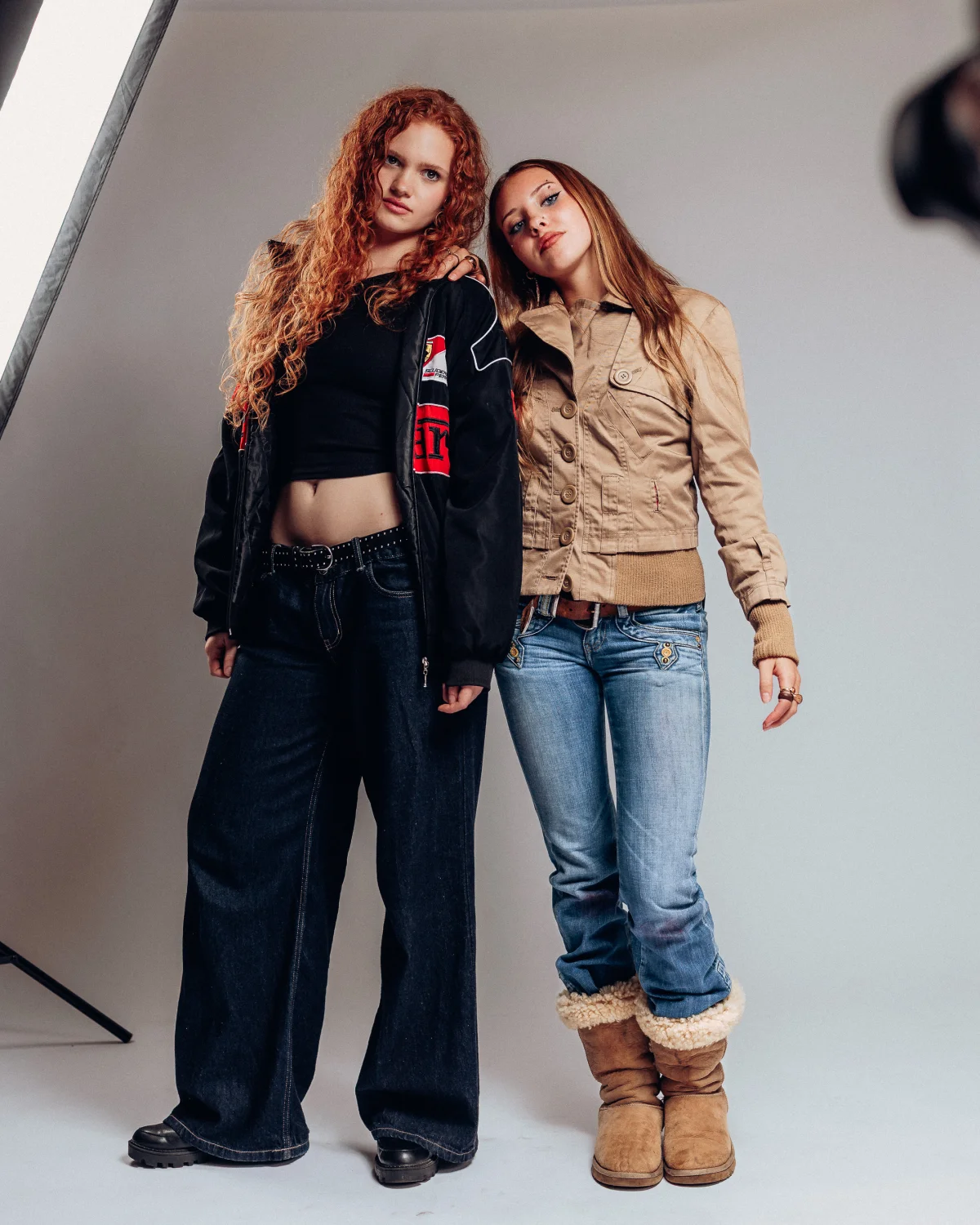 Two young women posing in a studio wearing Y2K-style streetwear and boots.