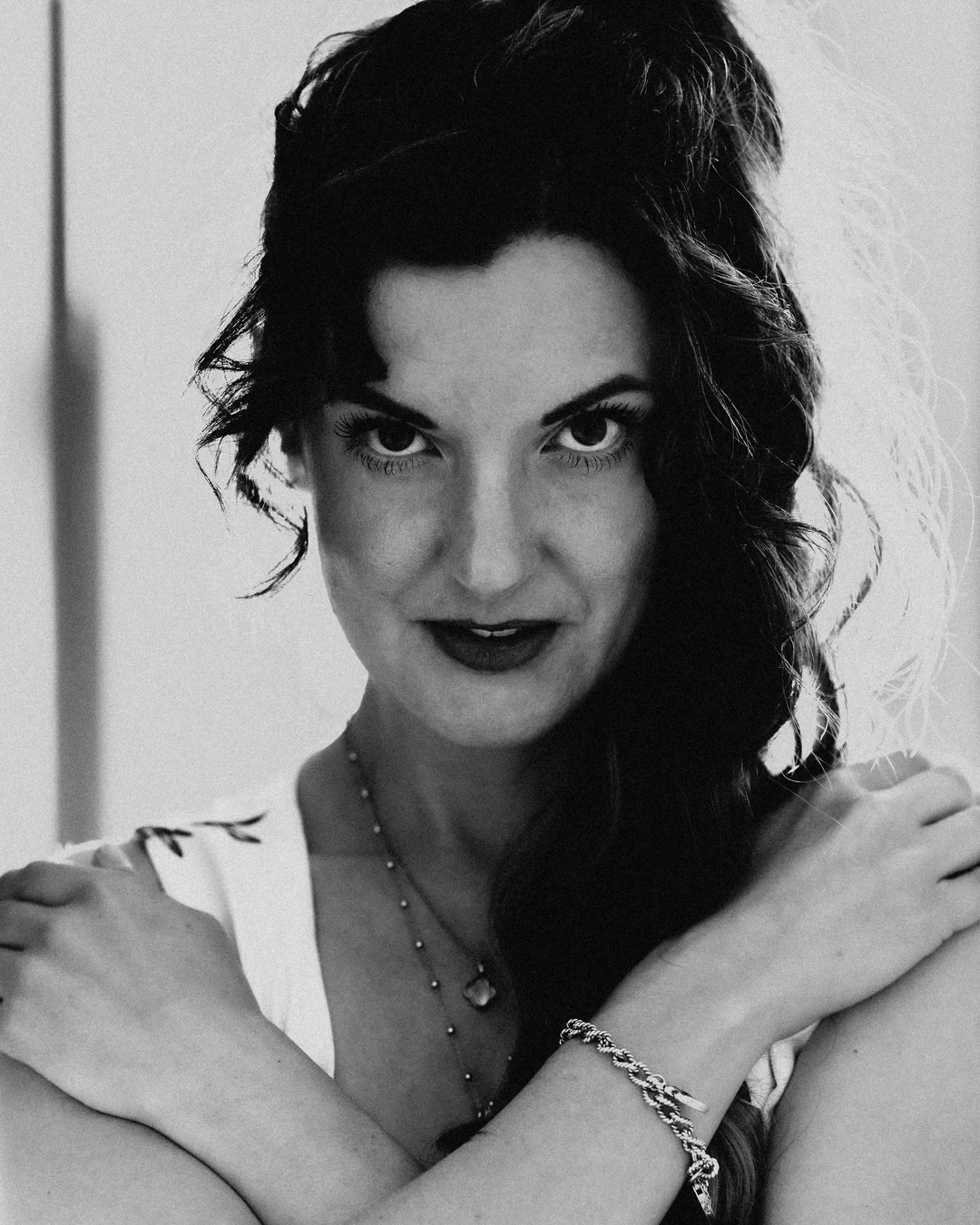 Black and white close-up portrait of a woman with dark wavy hair and an intense gaze.
