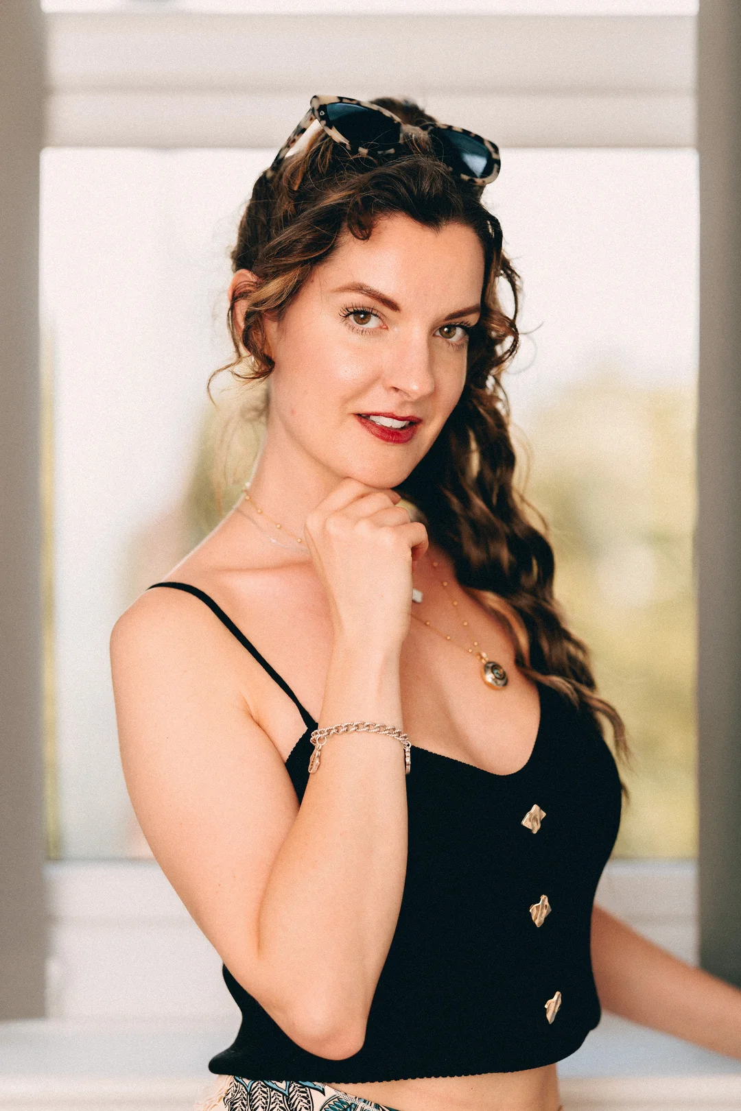 Portrait of a woman with wavy brown hair and a black top, posing with a thoughtful expression.