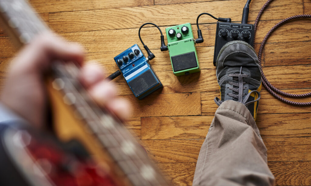 a person playing a guitar and using effect pedals Bild