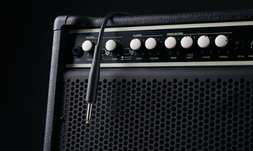 Close up of Black guitar amplifier with jack cable on black background.